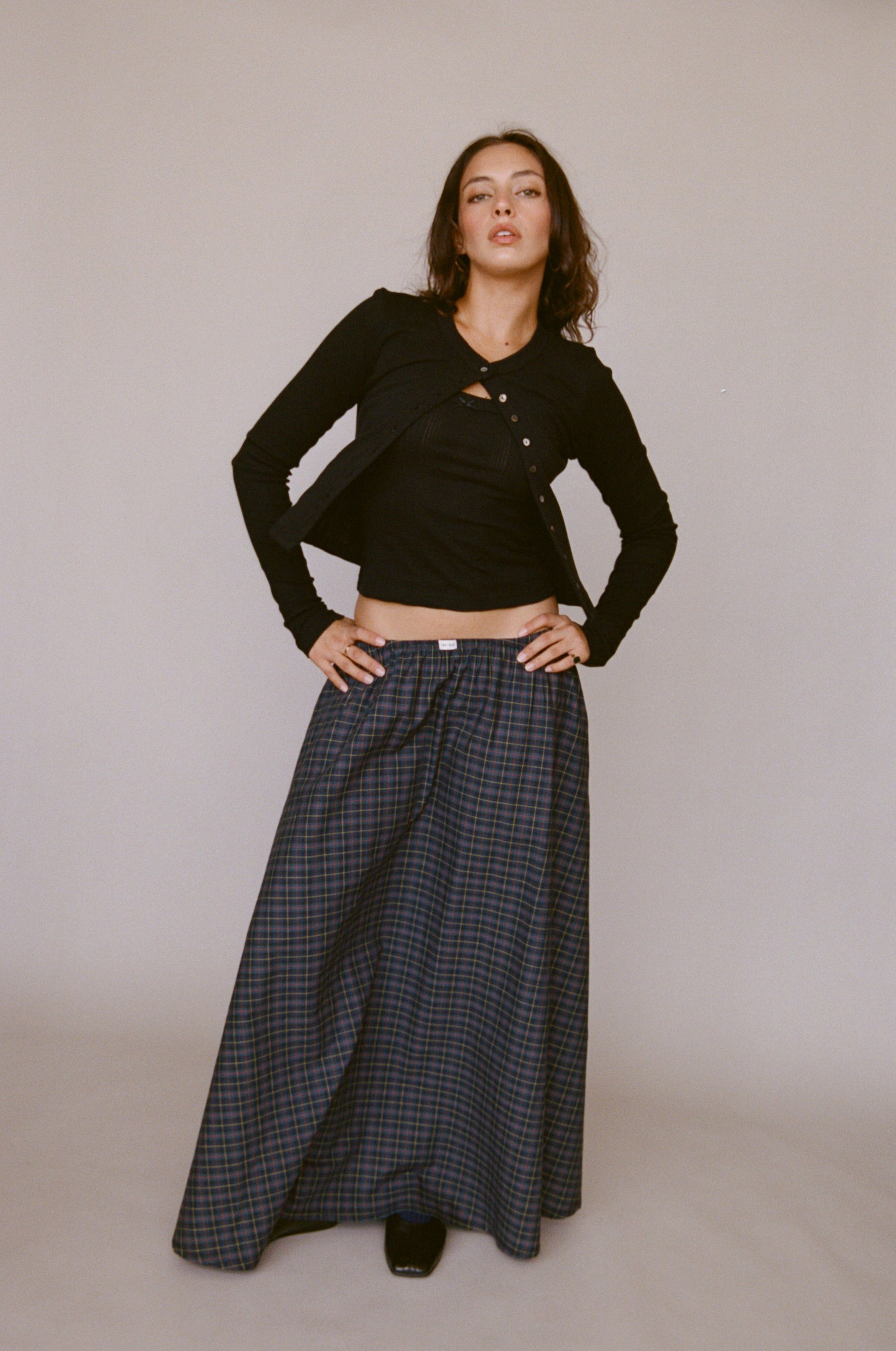Black cropped cardigan with button front paired with navy plaid wide-leg pants, full-length studio shot on model