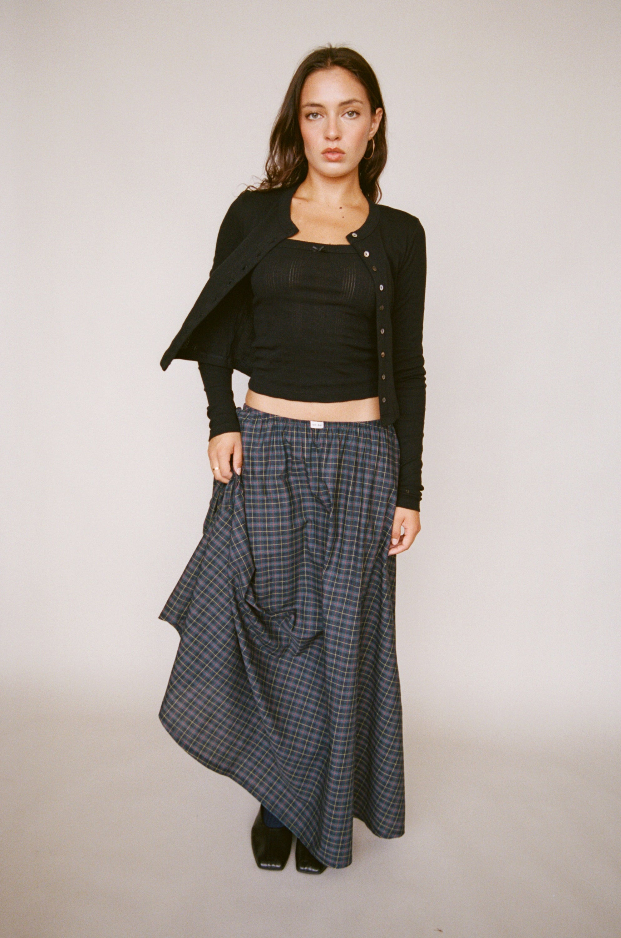 Black ribbed crop top and cardigan set with plaid wide-leg pants, styled with black heeled boots on neutral background