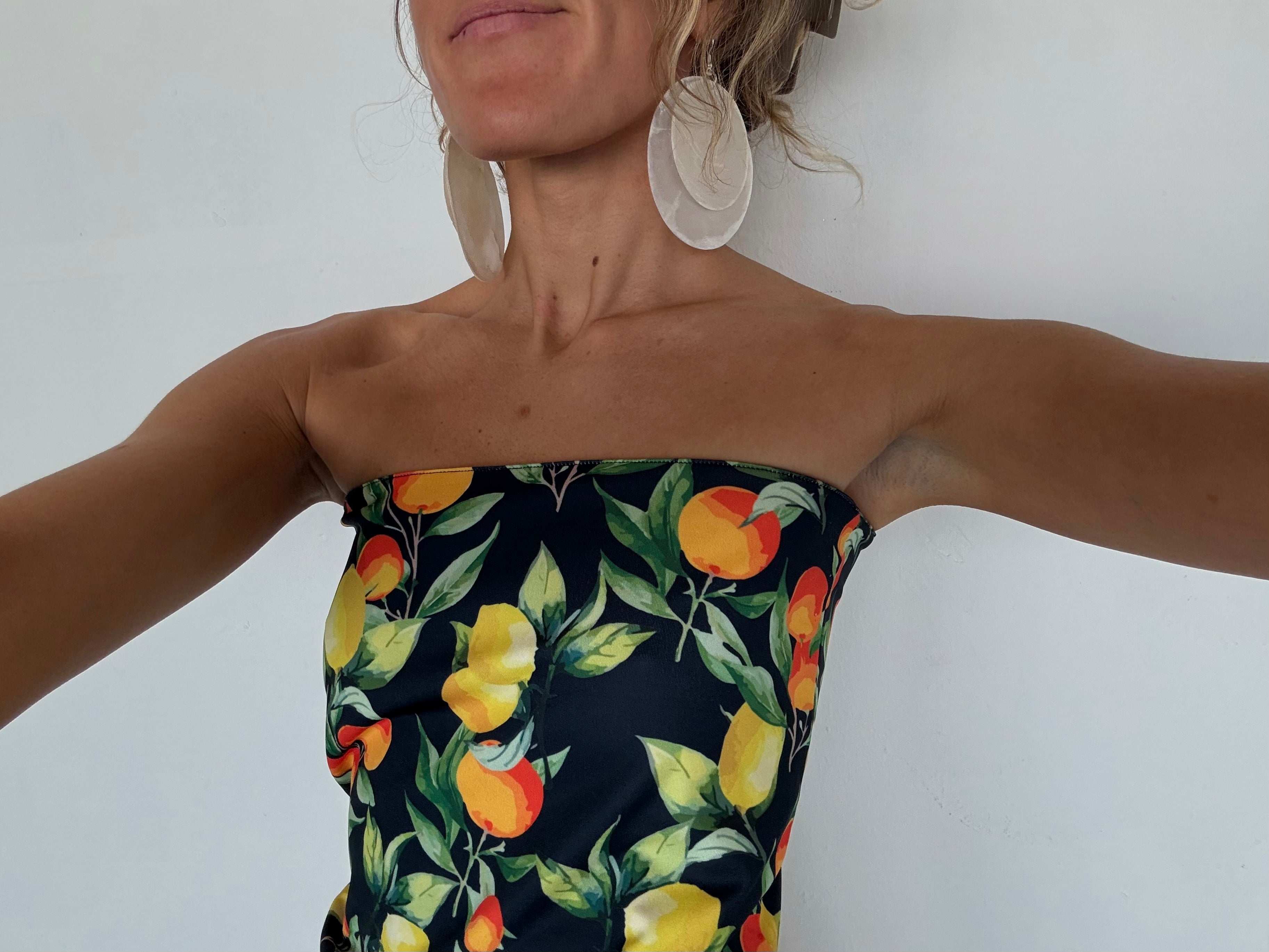 Woman wearing strapless navy blue tube top with citrus fruit print featuring lemons, oranges, and green leaves