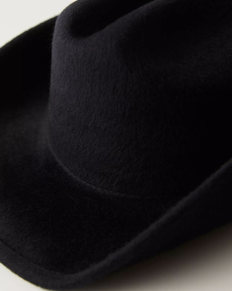 Black felt fedora hat with wide brim and ribbon band detail, shown in close-up profile view