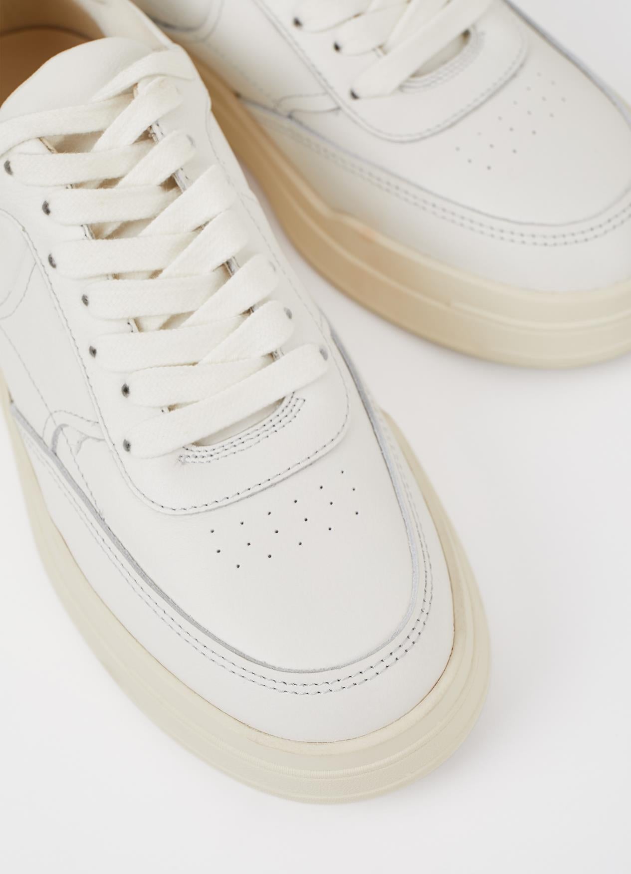 White leather sneakers with cream-colored soles and traditional lace-up closure, featuring clean minimalist design with perforated details