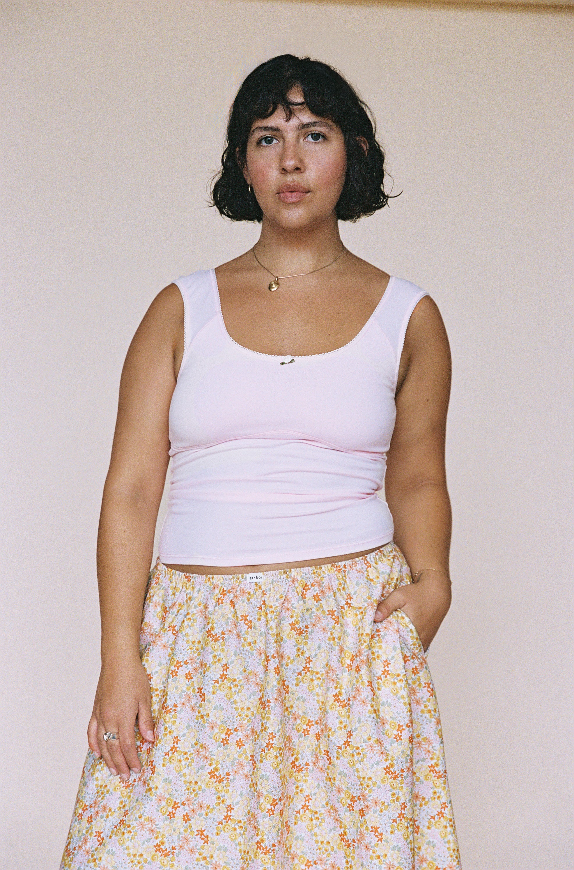 Light pink sleeveless tank top with scoop neckline, made of stretchy ribbed fabric with gathered waist detail