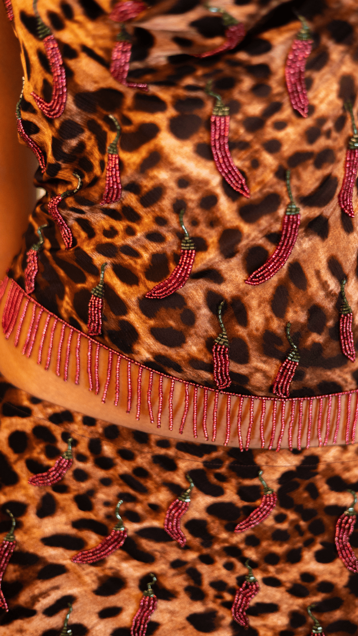Leopard print silk fabric with pink beaded embellishments and fringed trim detail in warm brown tones