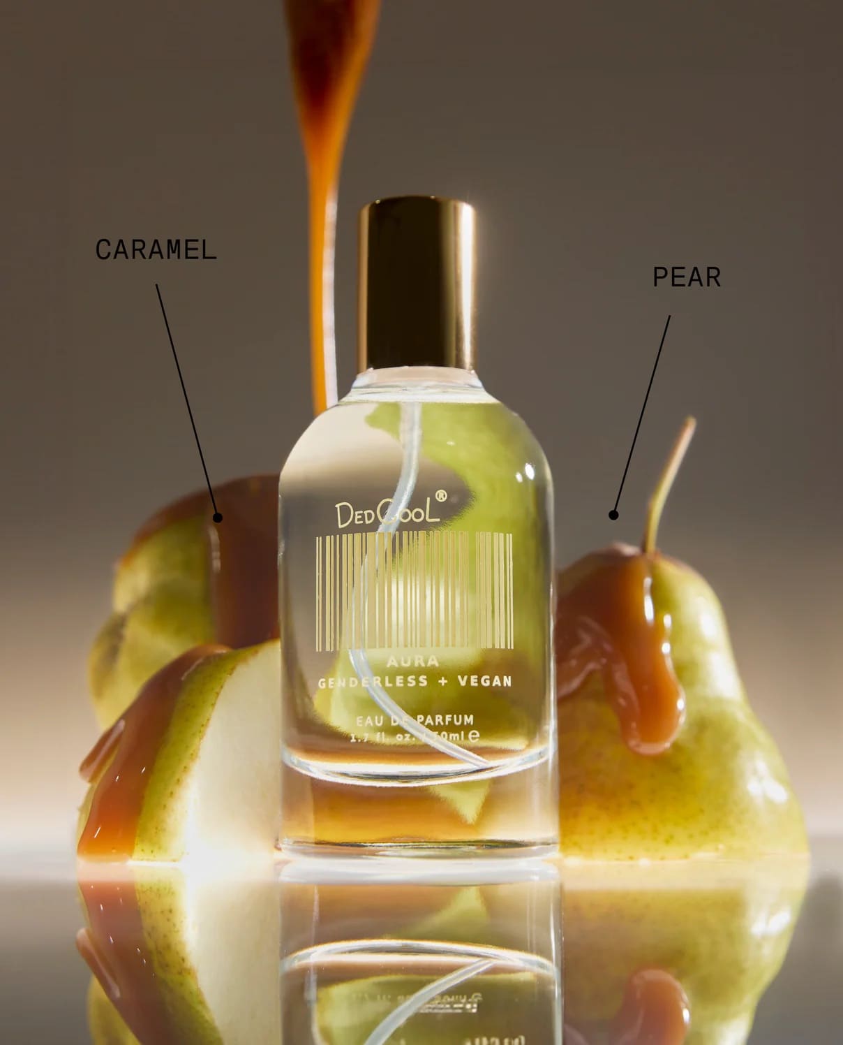 DedCool Aura genderless vegan eau de parfum bottle with yellow-green liquid, gold cap, flanked by caramel apples and pears