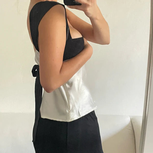 Person wearing a black top and white shirt with a neutral background