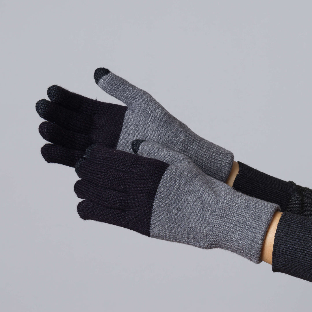 Two-tone knit gloves in gray and black with ribbed cuffs, shown on hands against gray background