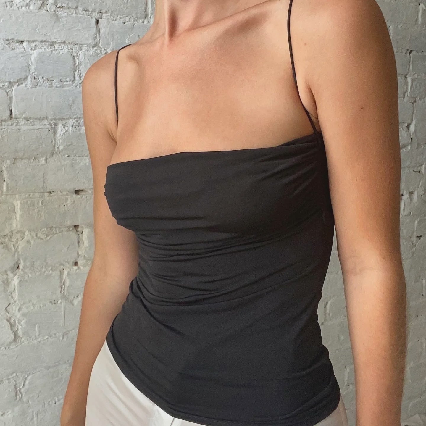 Person wearing a black strapless top against a gray brick wall