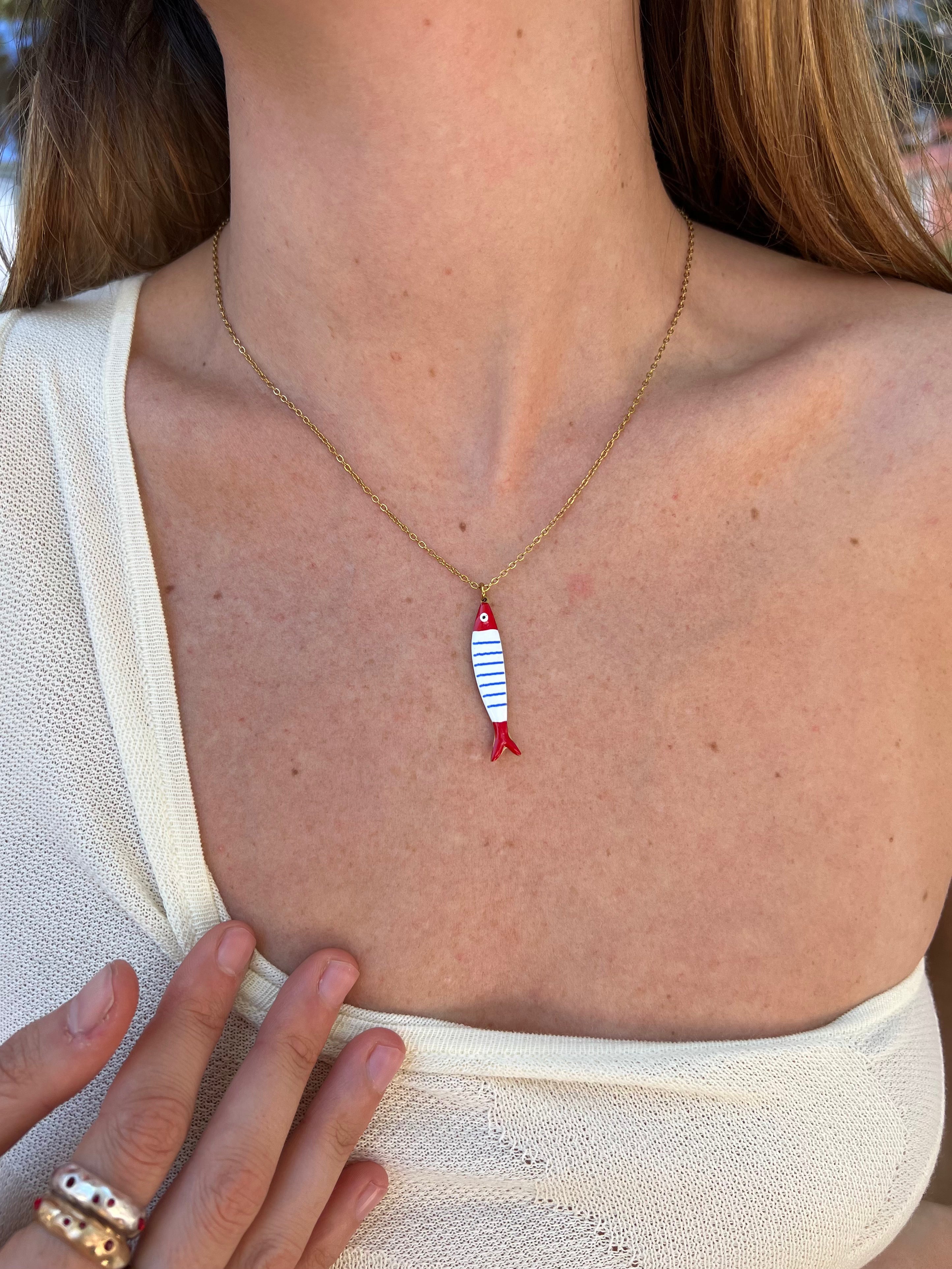 Gold chain necklace with enamel fish pendant featuring red head and tail with blue and white striped body