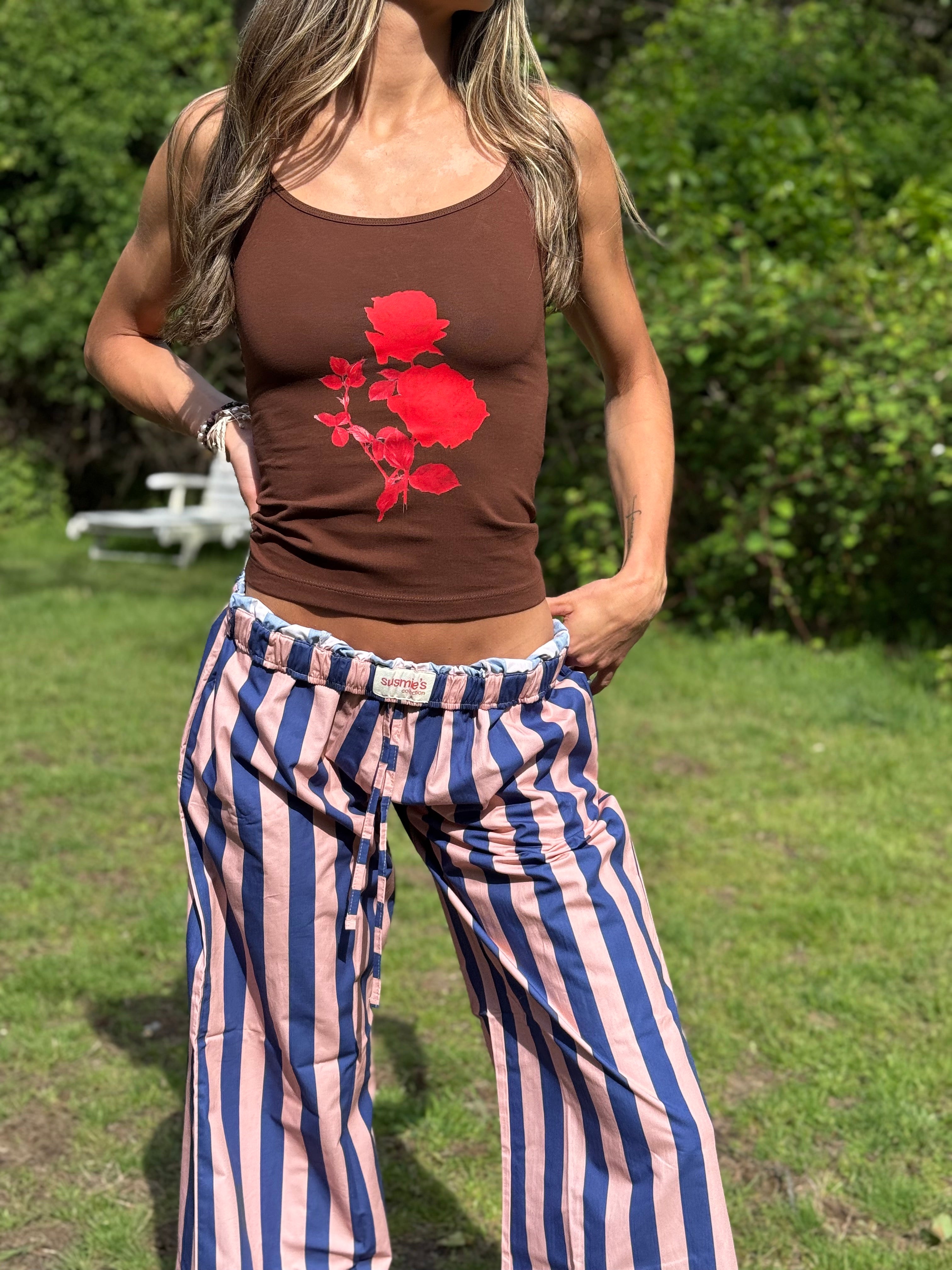 Brown tank top with red rose graphic and blue-pink striped wide-leg pants outfit displayed on model outdoors
