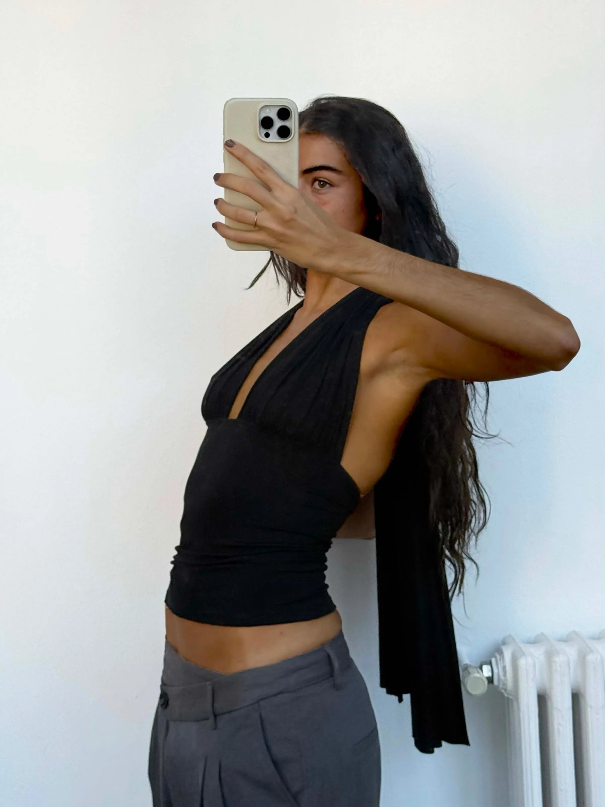 Black asymmetrical one-shoulder crop top with draped fabric detail and cutout design