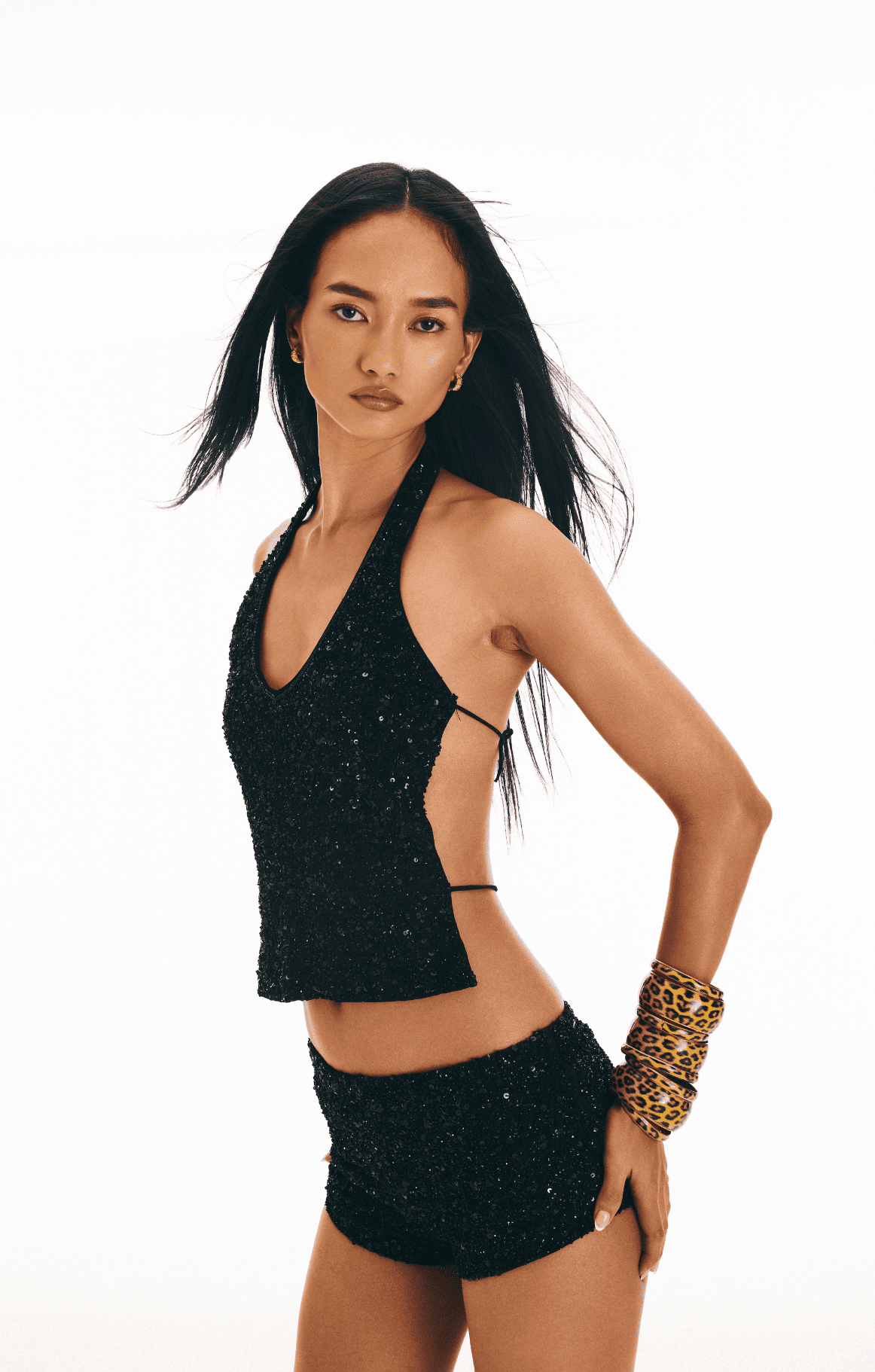 Black sequined halter top and shorts set with cutout sides, worn with leopard print cuff bracelet