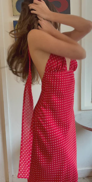Woman wearing a red polka dot dress with sheer sides in a room.