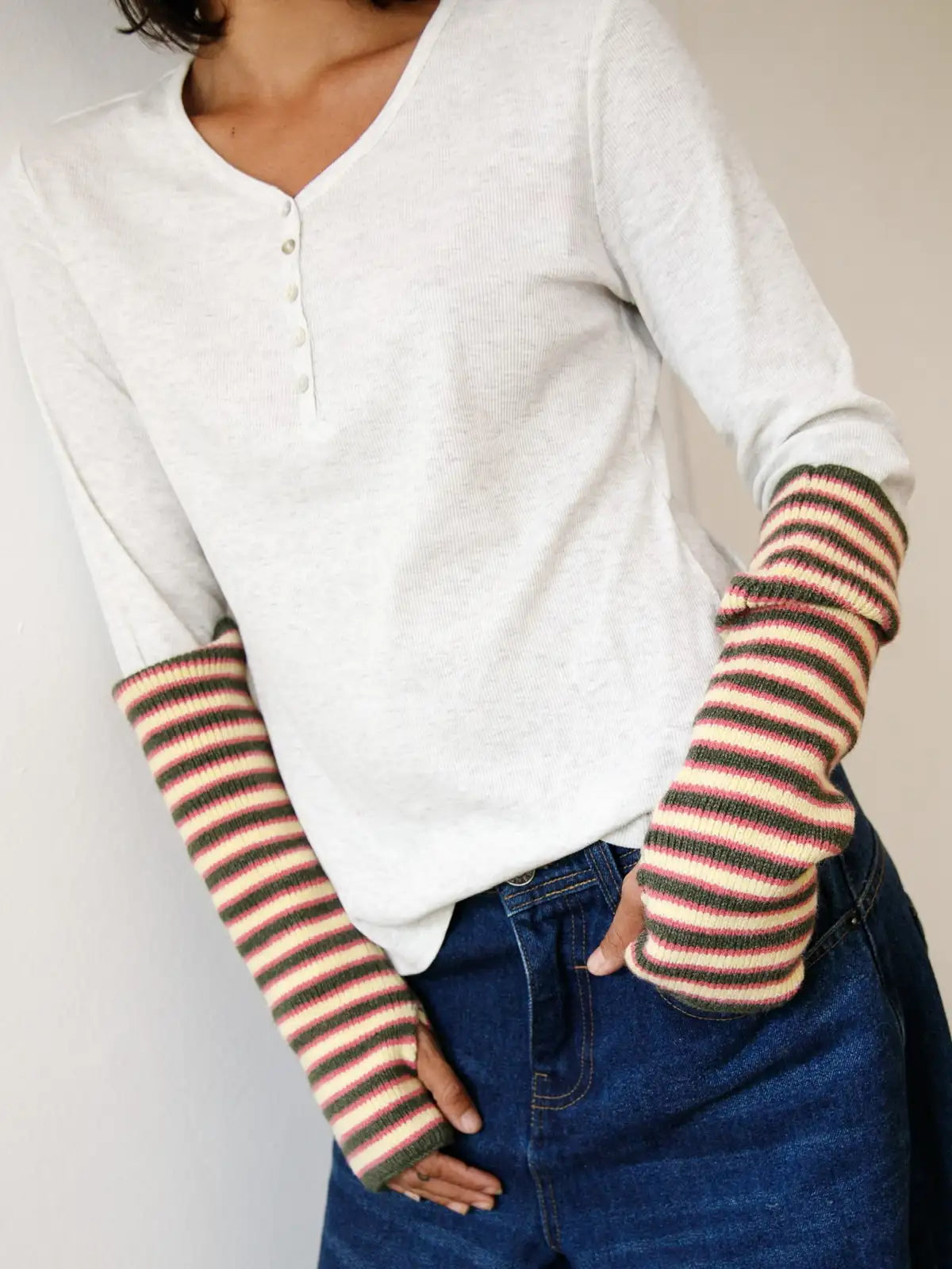 White ribbed henley shirt with colorful striped knit arm warmers, worn with blue jeans