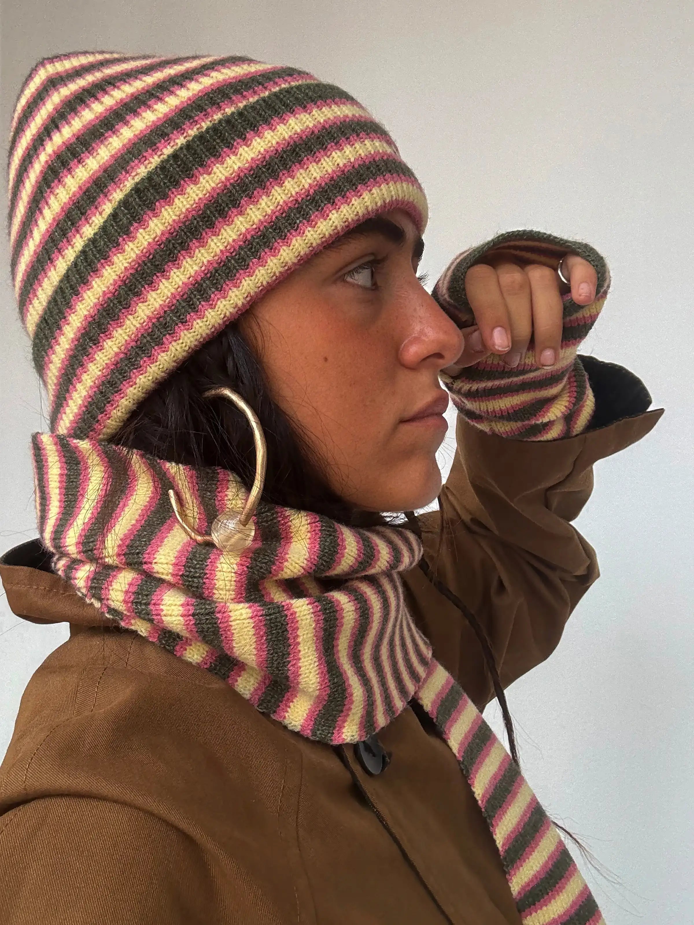 Striped knit bucket hat and scarf set in yellow, pink, and brown stripes with matching fingerless gloves worn by model