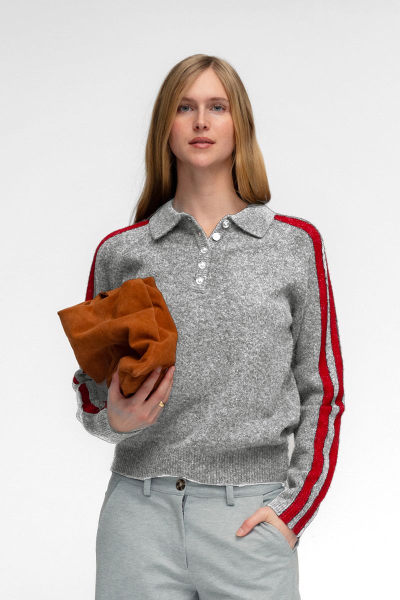 Gray knit polo sweater with red side stripe detail and silver buttons, paired with light gray trousers.