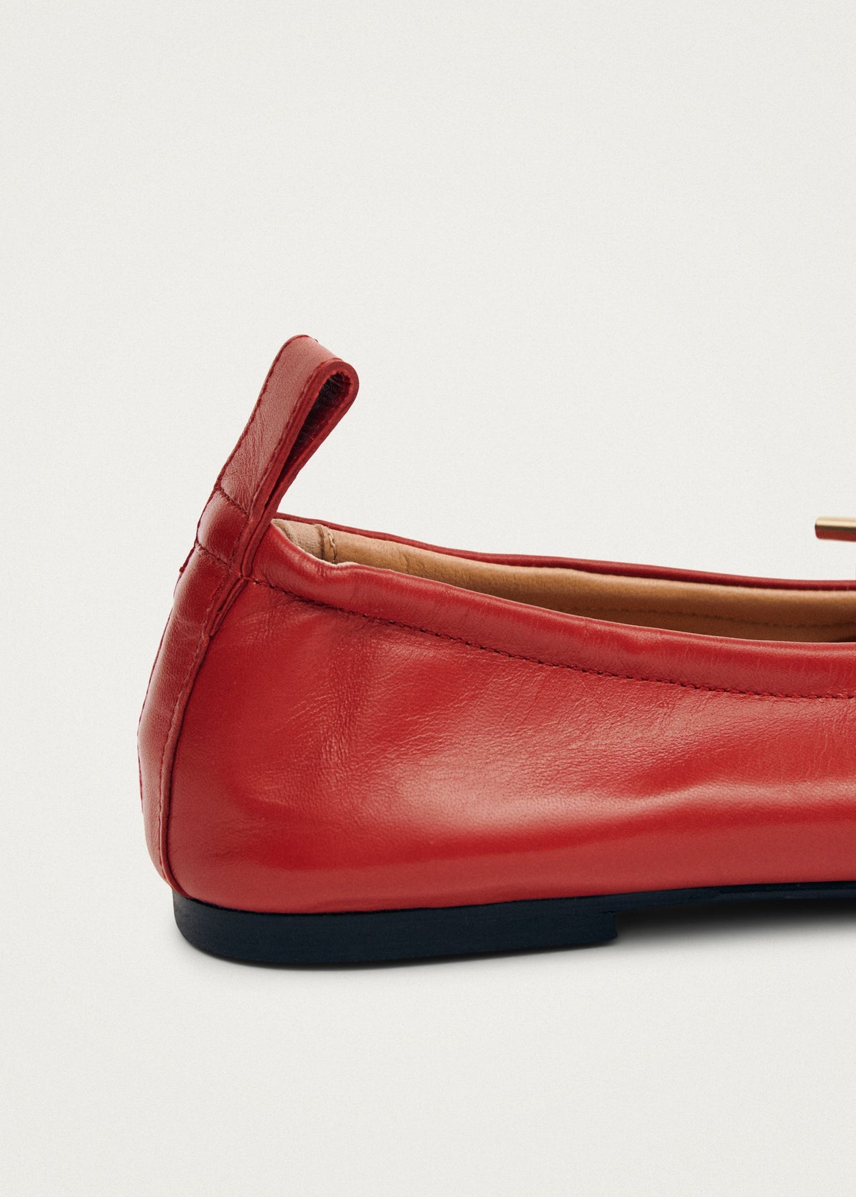 Red leather ballet flat with gold hardware detail, pull tab at heel, and dark rubber sole.