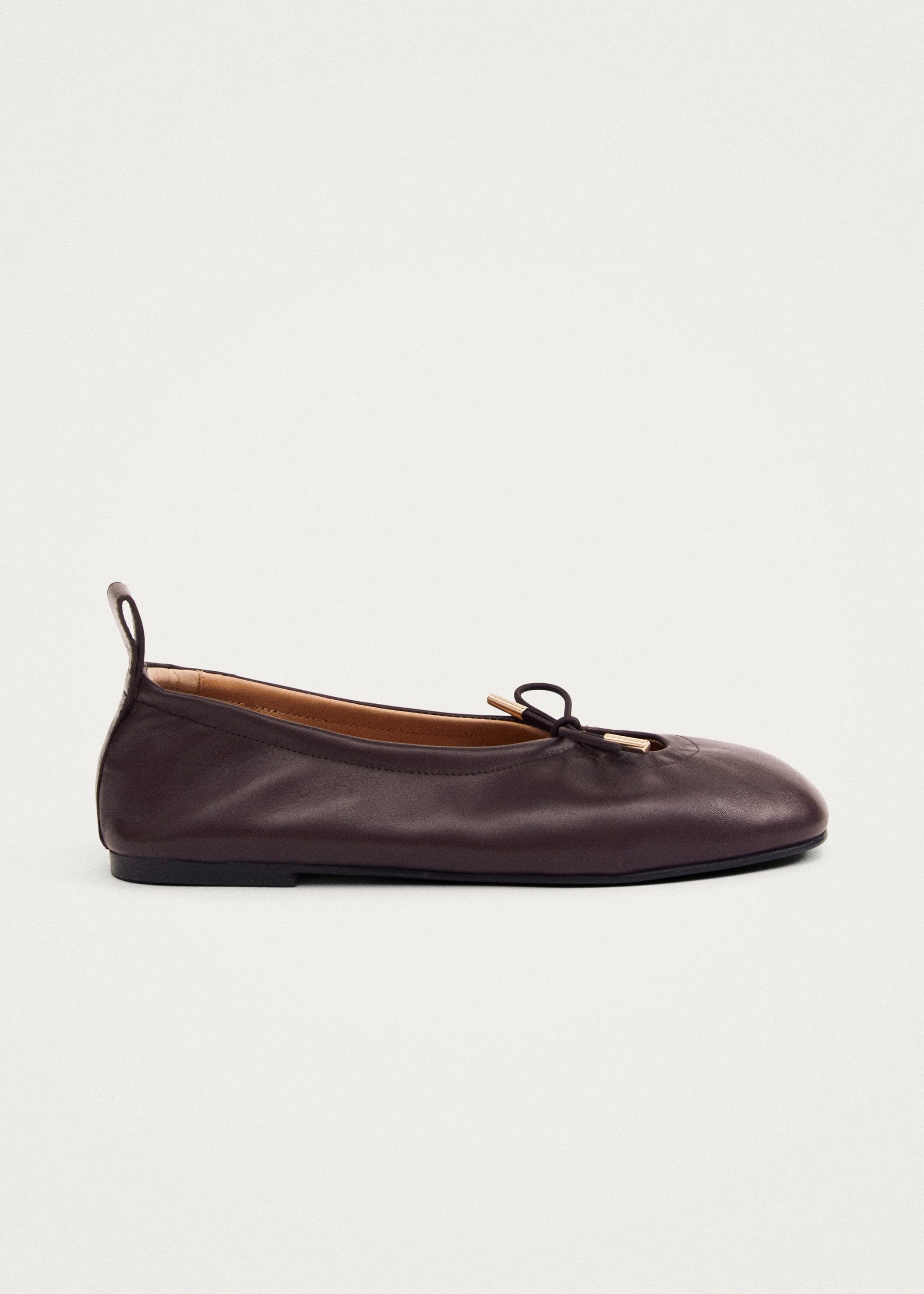 Dark brown leather ballet flat with bow detail and pull tab, side view on beige background
