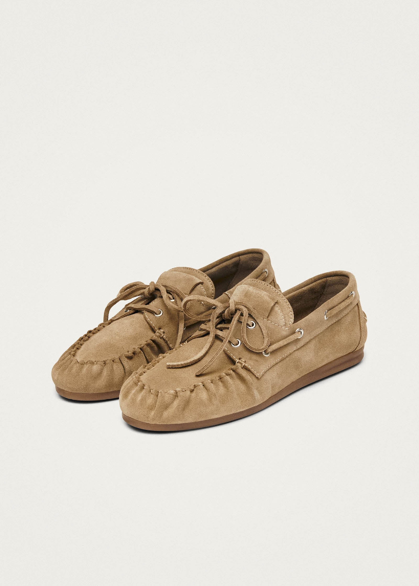 Tan suede moccasin loafers with lace-up detail and brown rubber sole, displayed as a pair on neutral background