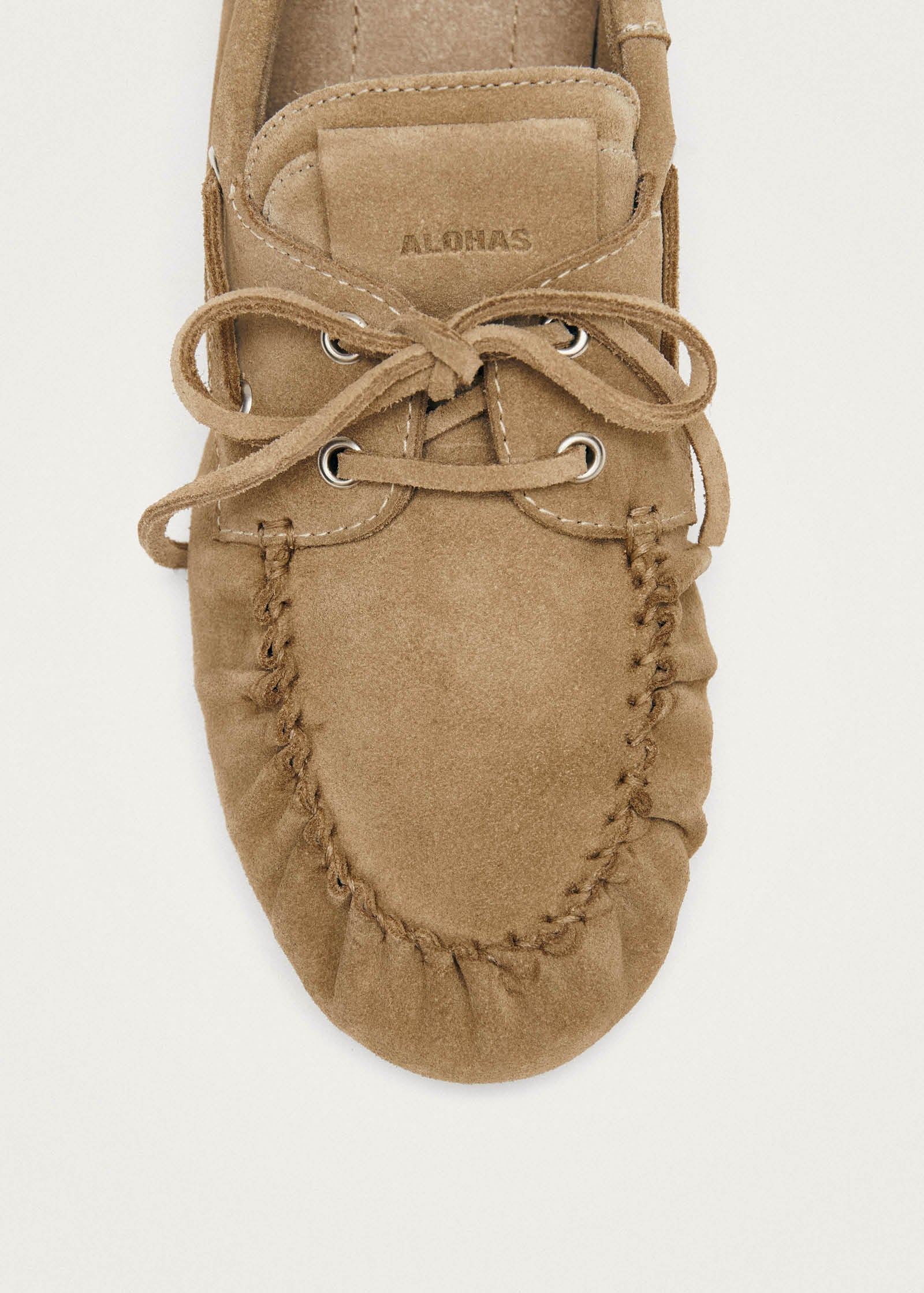 Beige suede moccasin with laces and hand-stitched detail, ALLOMAS branding visible on tongue