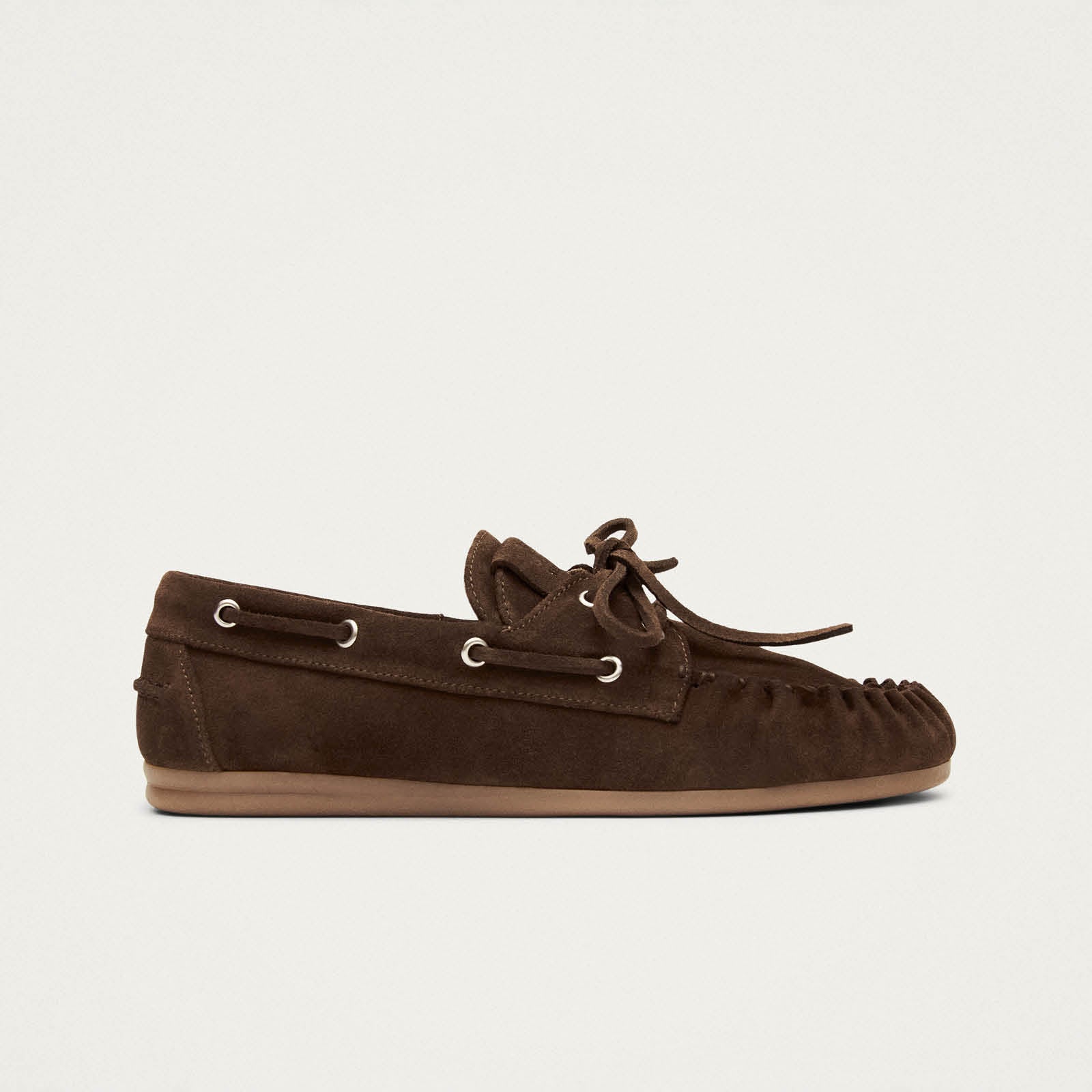 Brown suede moccasin slippers with lace-up detail and rubber sole, shown in side profile view