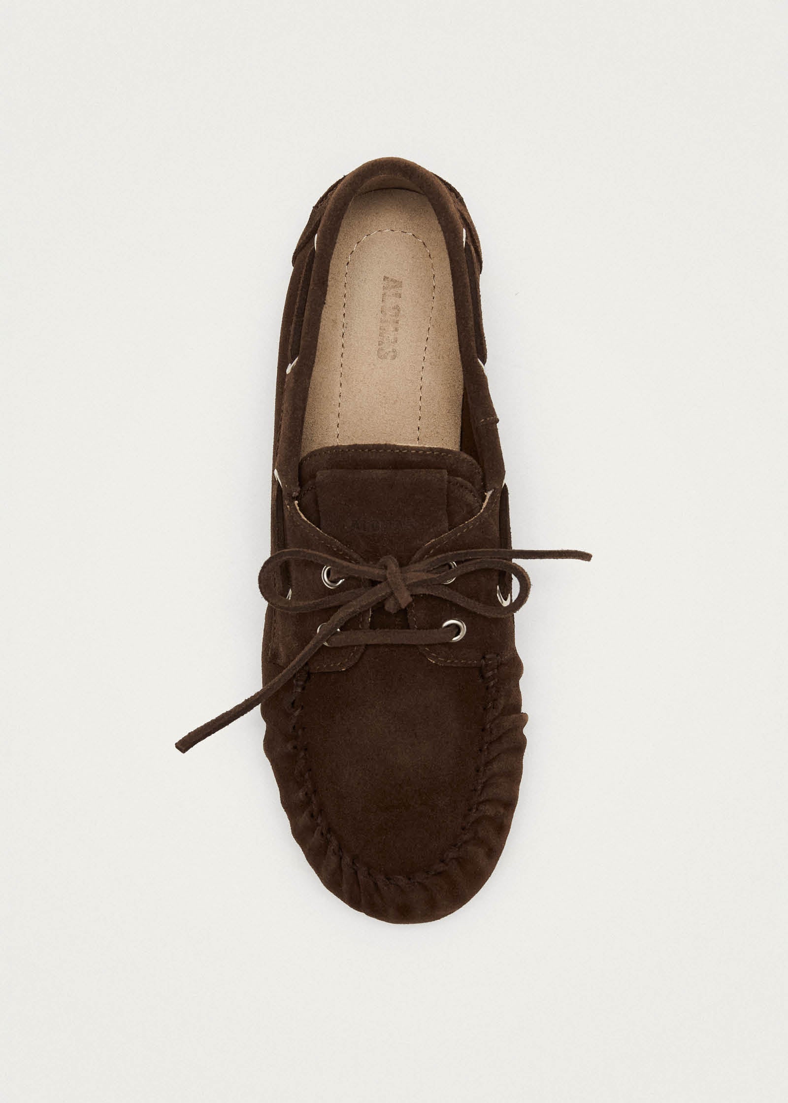 Dark brown suede moccasin with bow tie lacing and stitched detail, viewed from above on light background