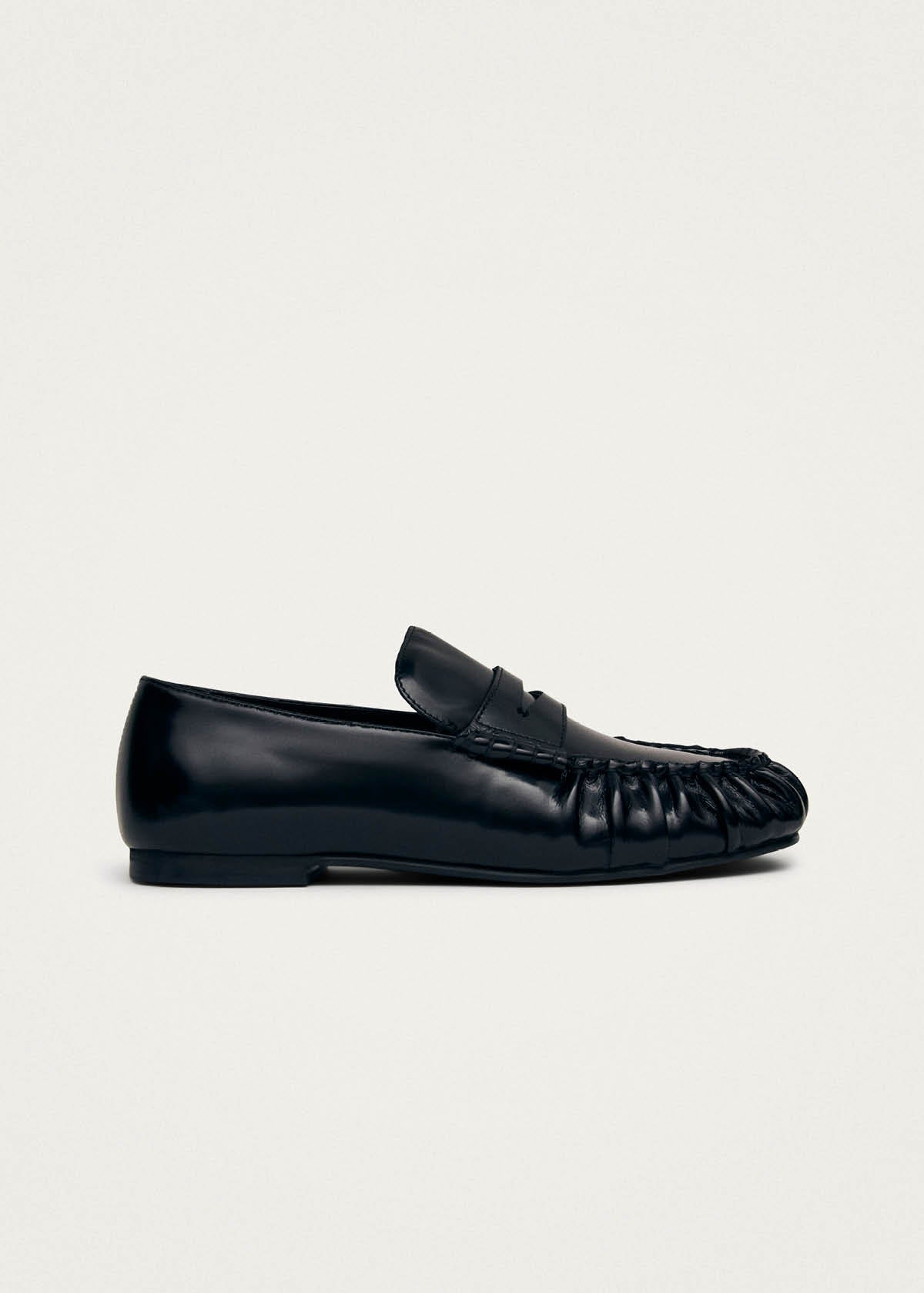 Black leather loafer with gathered toe detail and penny strap across vamp