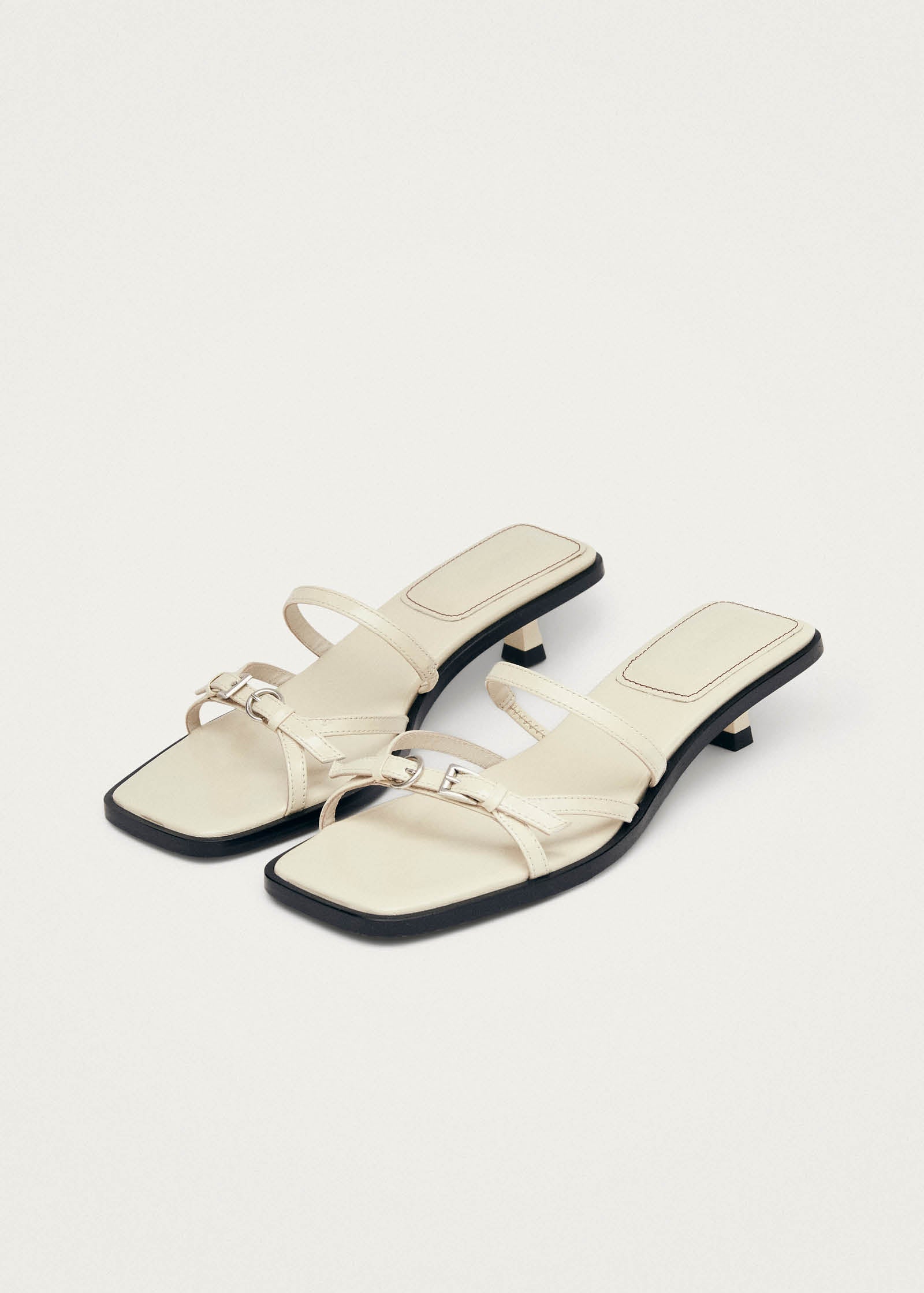 Cream leather strappy sandals with black low heel and silver buckle detail