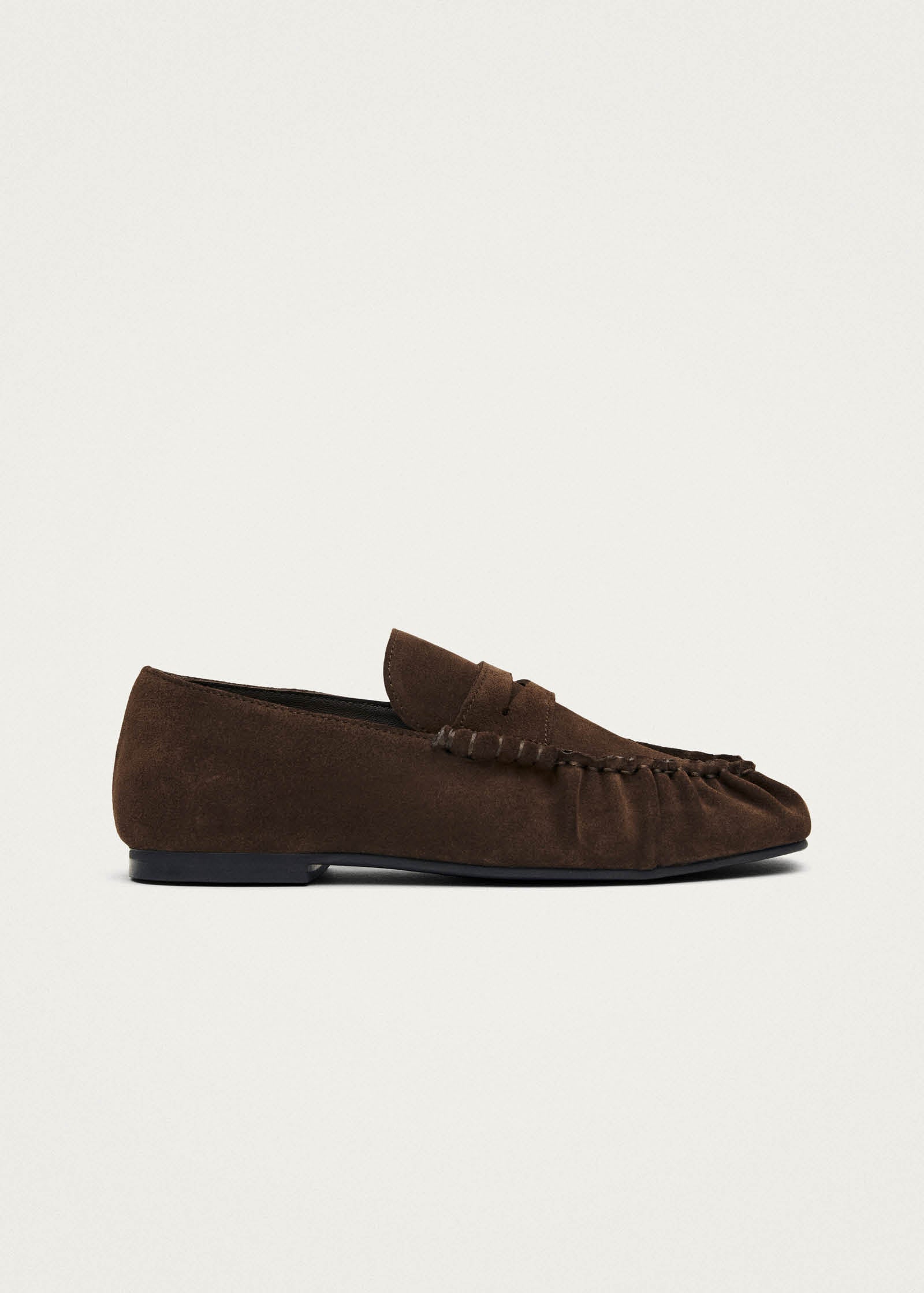 Brown suede moccasin loafer with penny strap and visible stitching detail on a black sole