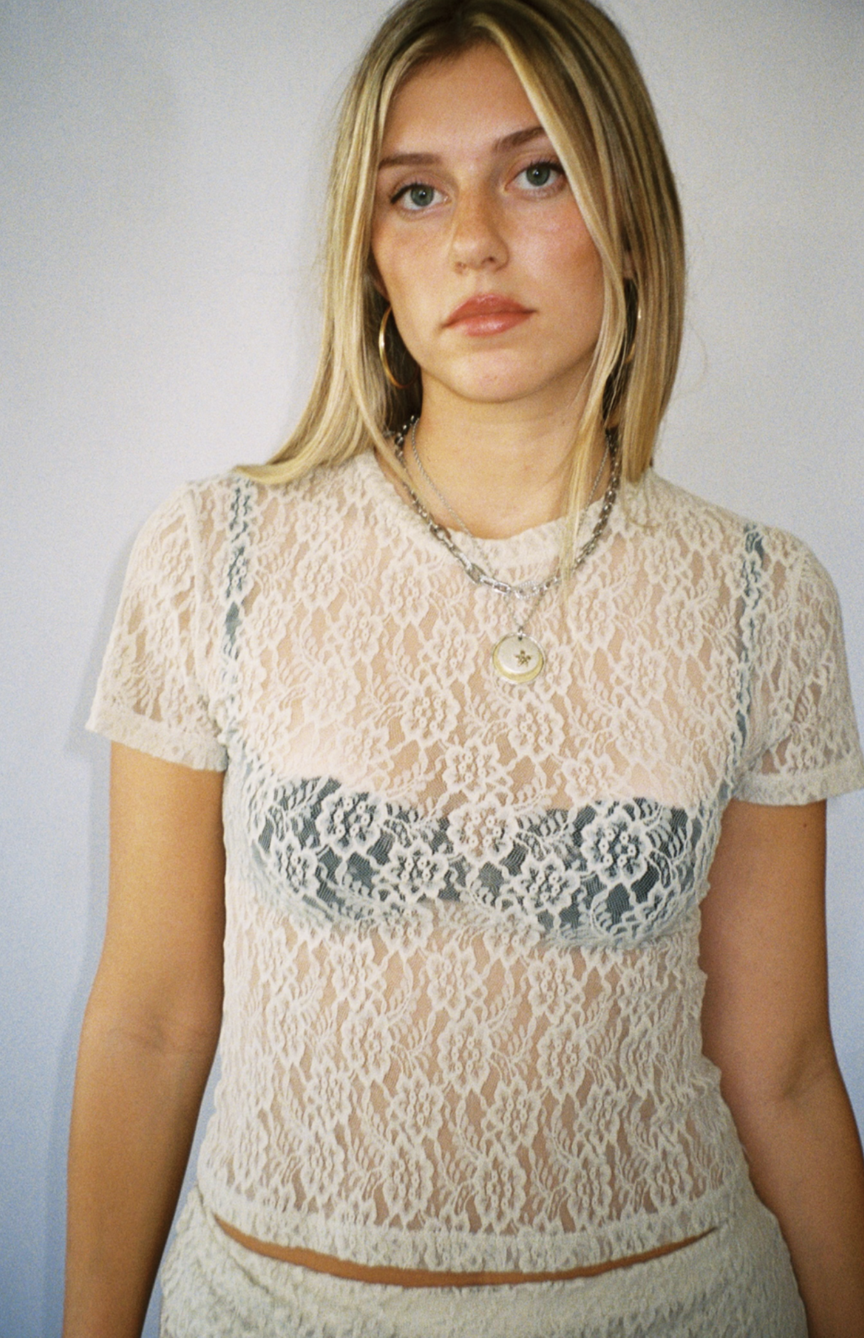 Cream-colored sheer lace short sleeve top with floral pattern and fitted silhouette