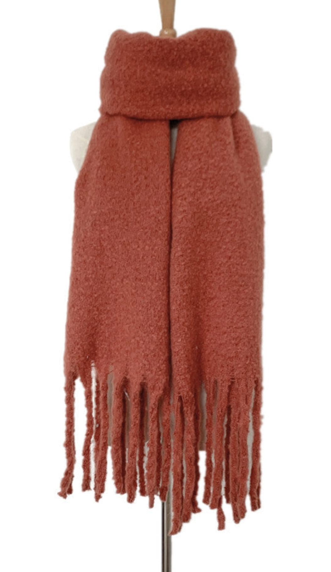 Rust-colored textured knit scarf with fringe tassels displayed on mannequin stand against white background