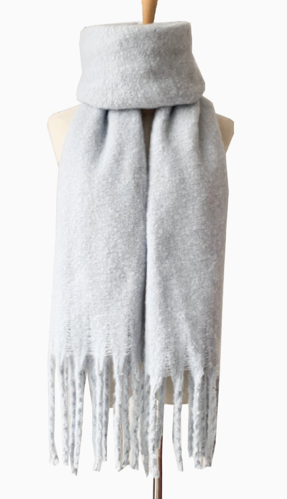 Light gray knit scarf with fringe detail draped on dress form mannequin
