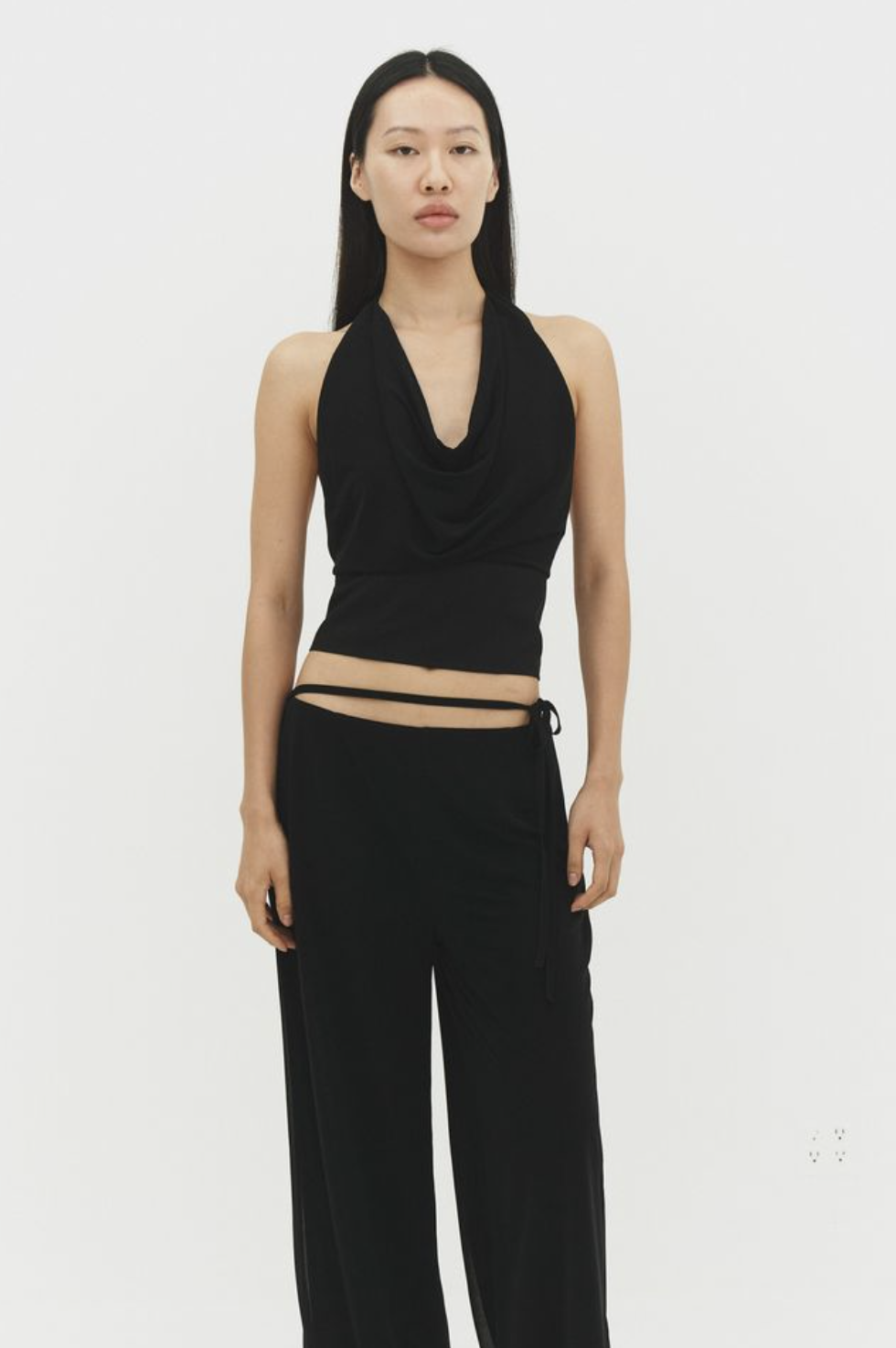 Black halter neck top with cowl neckline and wide-leg black pants, minimalist contemporary fashion outfit