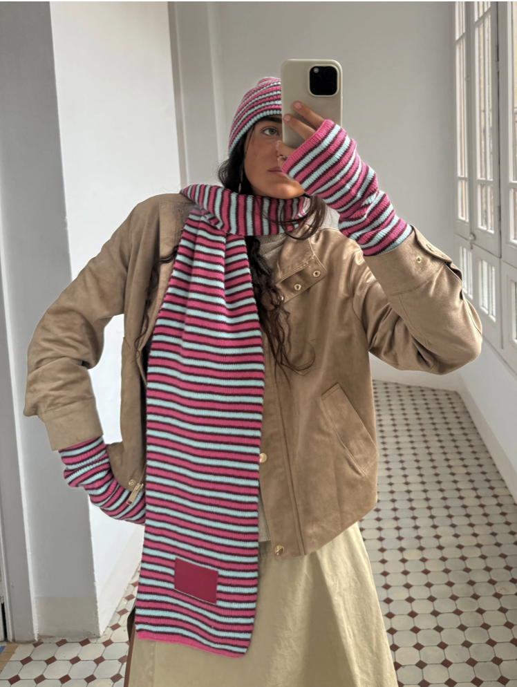 Striped knit scarf and beanie set in pink, white, and navy stripes with matching fingerless gloves styled with tan jacket
