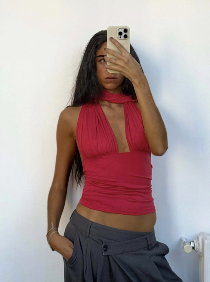 Red halter neck top with ruched details and keyhole cutout, paired with charcoal grey high-waisted trousers