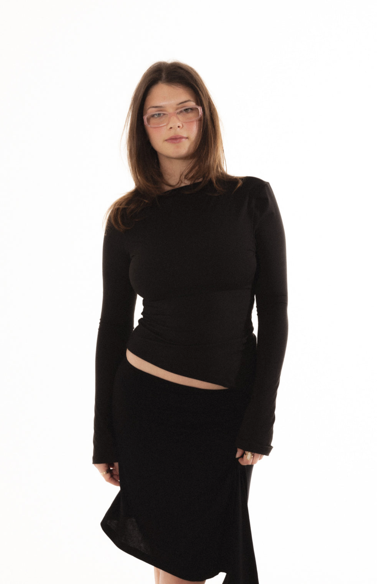 Black long-sleeve cropped top with cutout detail and matching asymmetric skirt, worn with tinted sunglasses