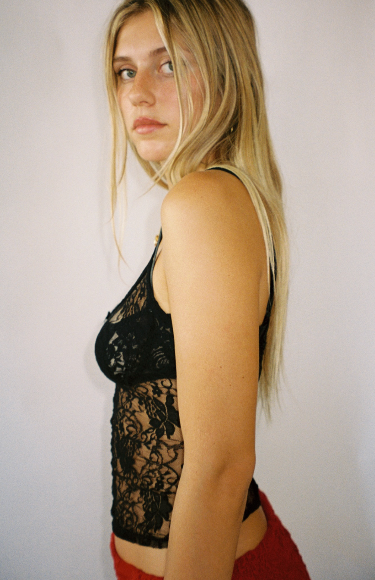 Black lace bodysuit with sheer floral pattern and adjustable straps, paired with red shorts