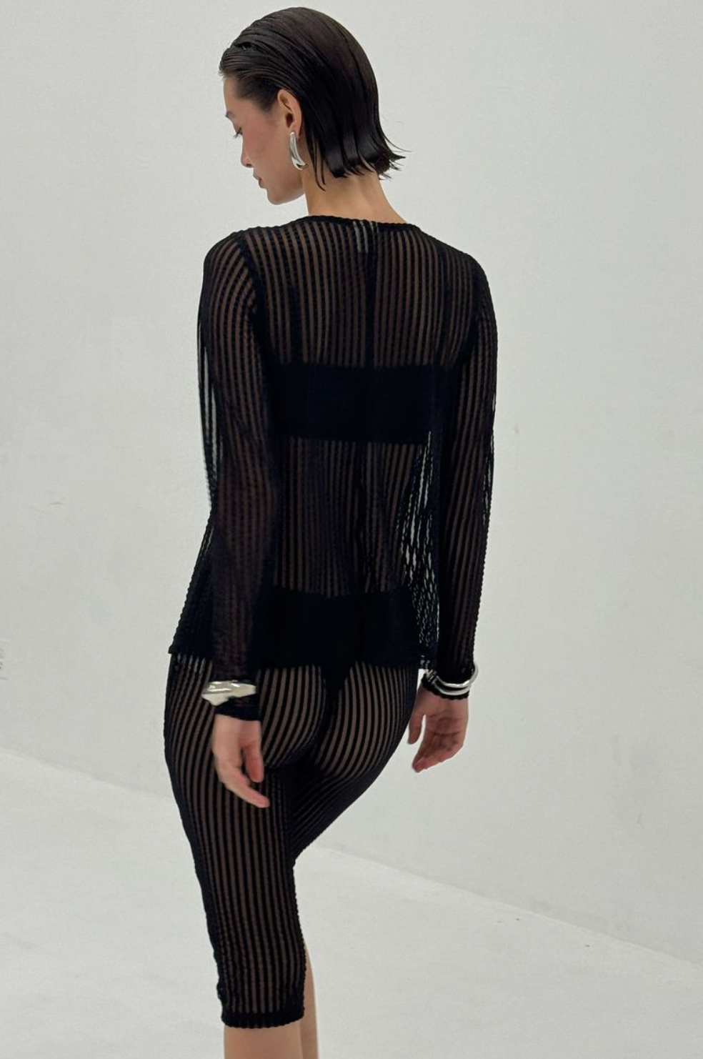 Black sheer striped knit top and skirt set with semi-transparent fabric showing layered undergarments beneath