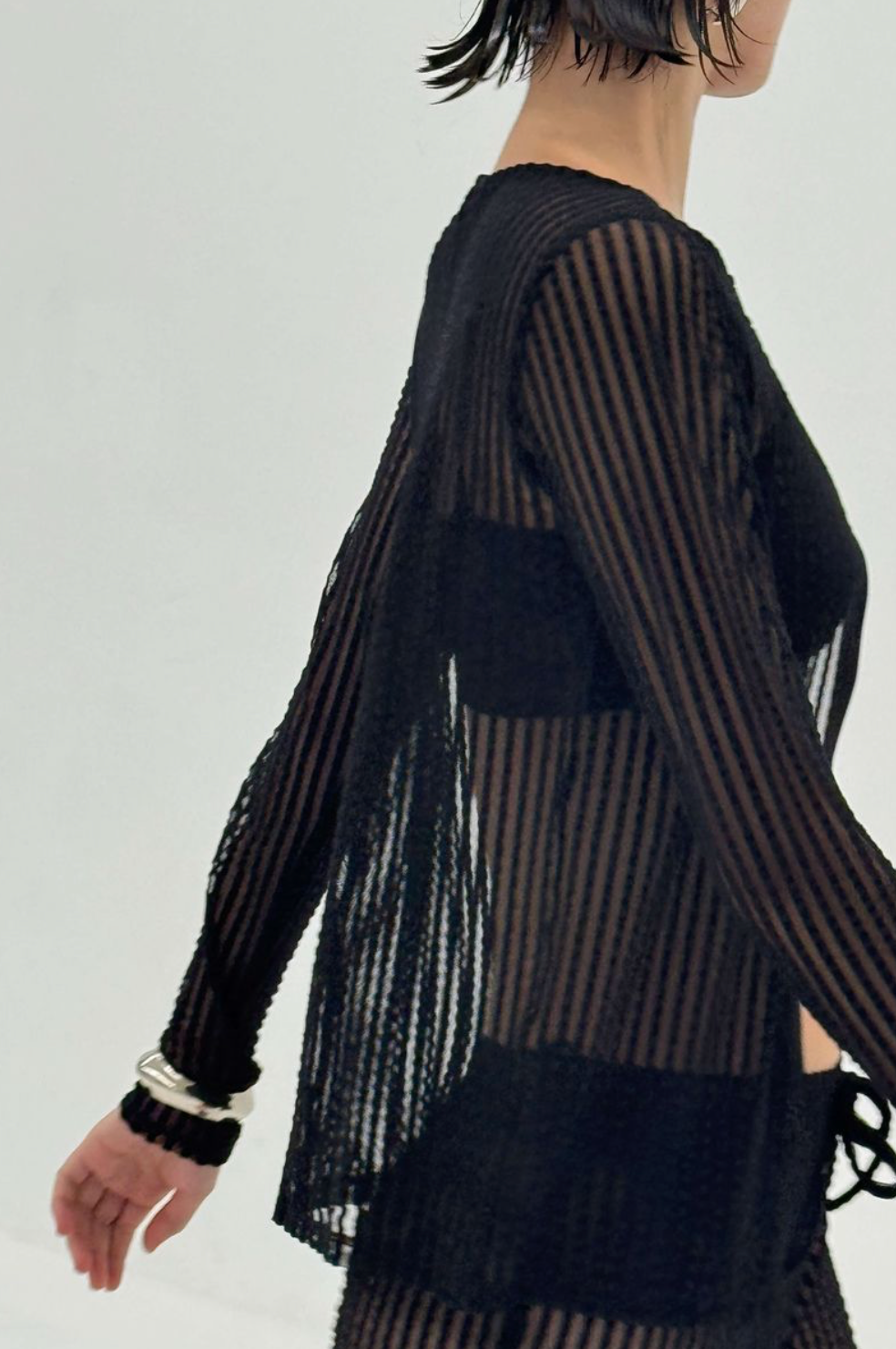 Black sheer striped long sleeve top with textured fabric and flared sleeves, shown from back view