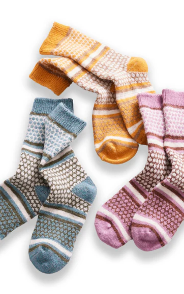 Three pairs of knitted wool socks in blue, yellow, and pink with geometric patterns and striped details on white background
