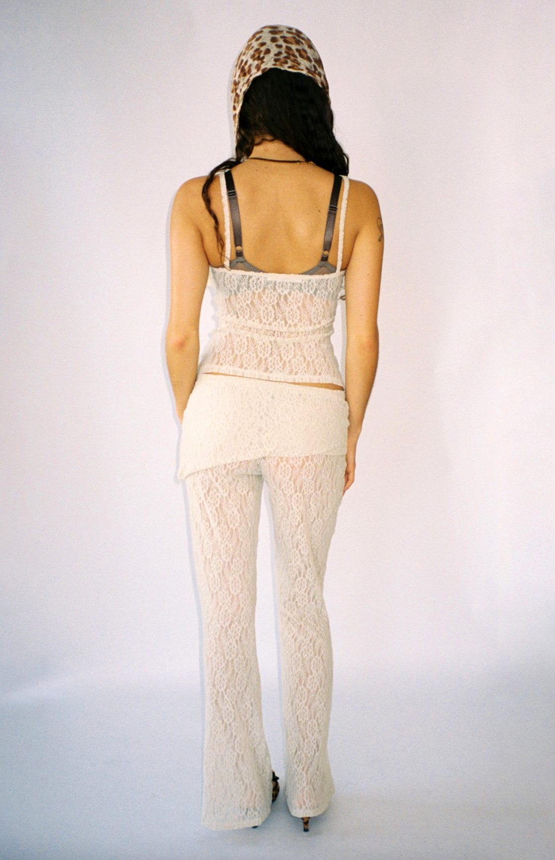 White lace cami top and pants set with visible bra straps and leopard print headscarf, shown from back