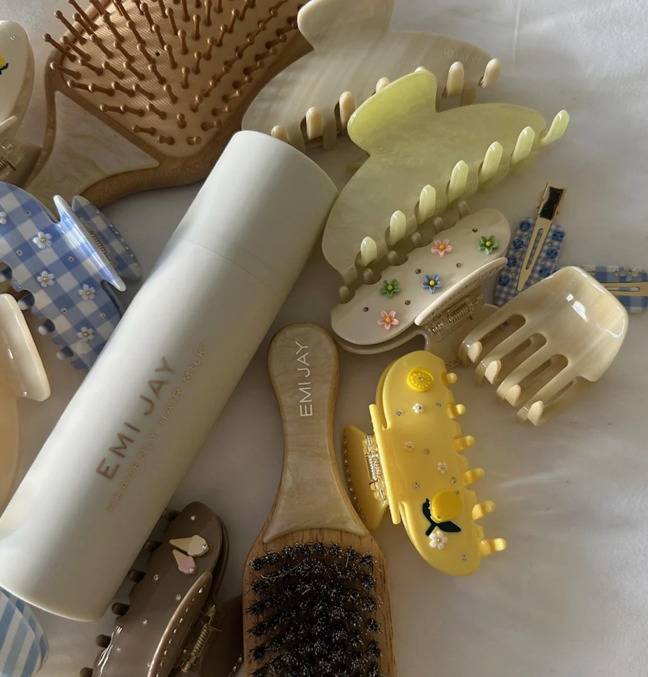 Collection of hair brushes and combs in pastel colors including yellow, cream, and white with decorative floral details
