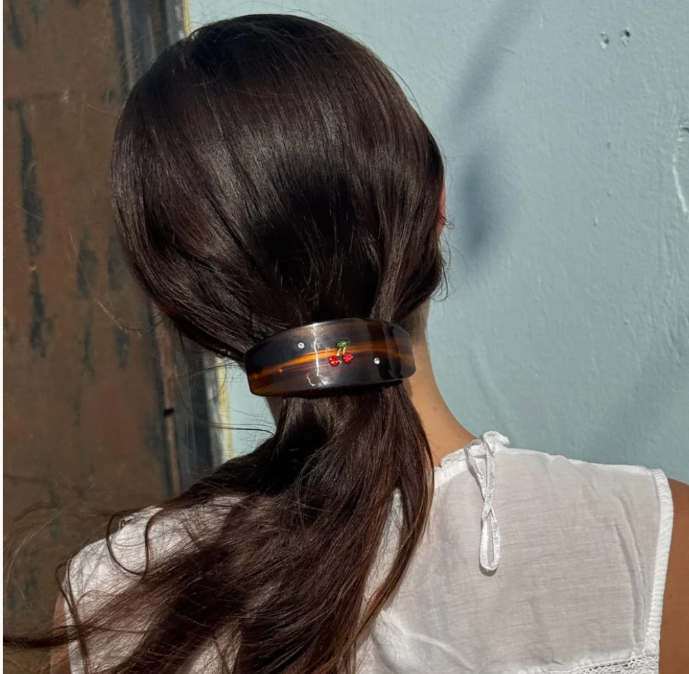 Dark tortoiseshell hair barrette with floral embellishment holding back long brown hair in a ponytail