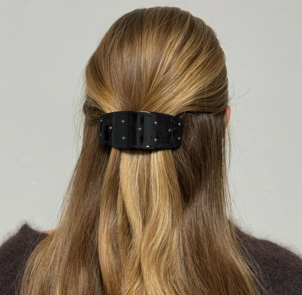 Black studded hair barrette clip holding back blonde hair in half-up style