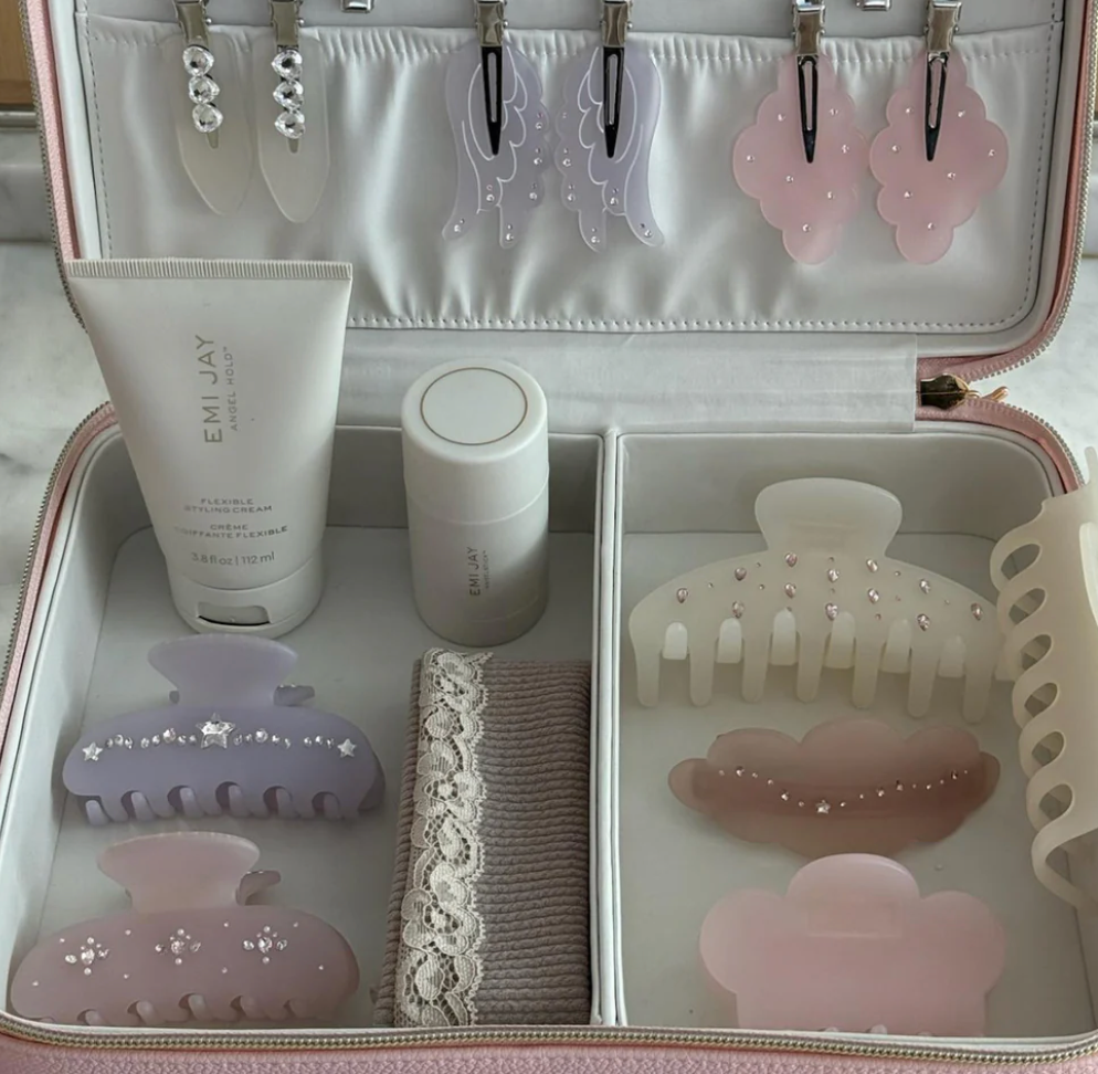 Pink and white travel jewelry and beauty organizer case with hair clips, styling cream, and decorative hair accessories