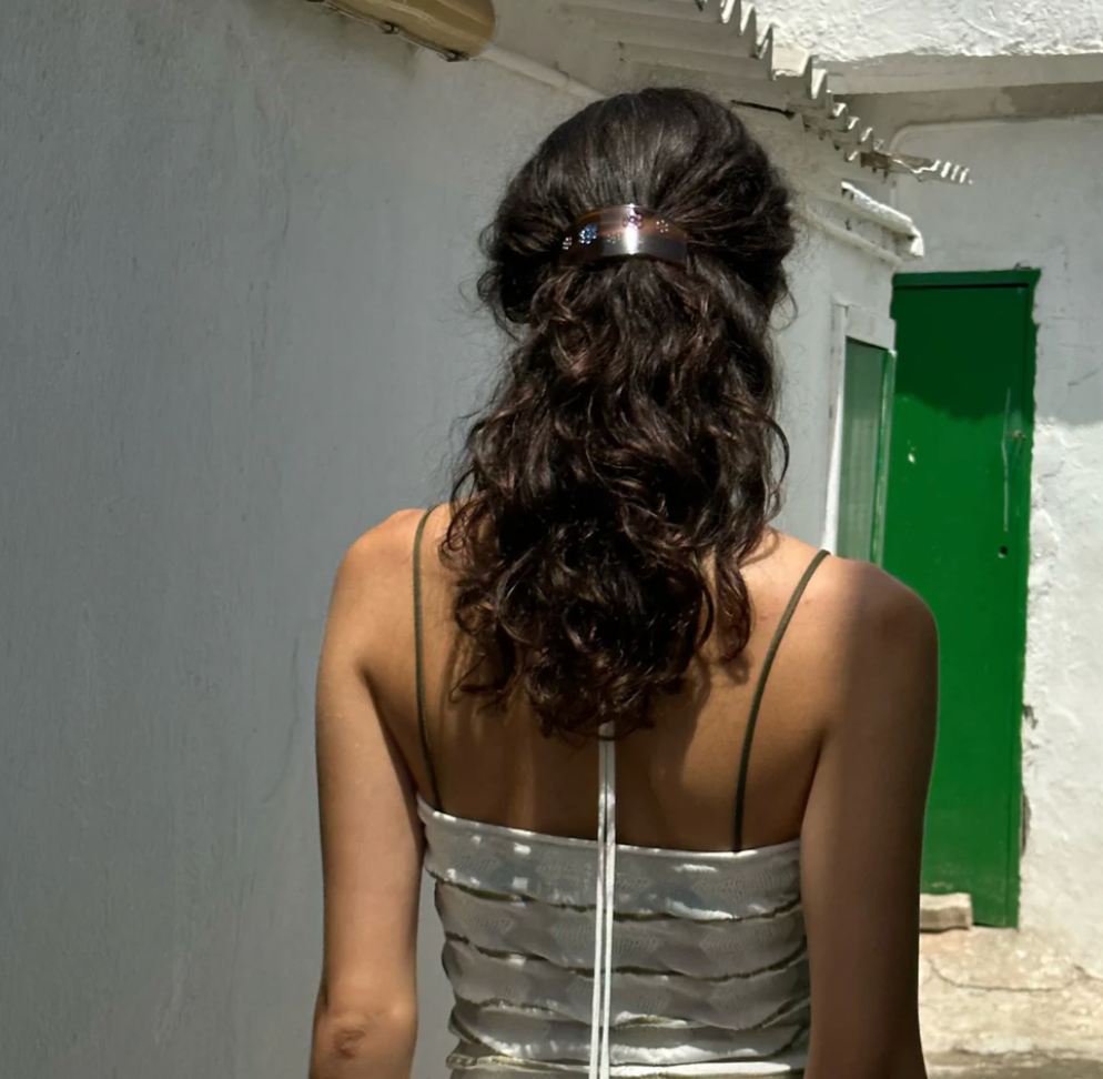 Rose gold crystal hair clip holding back curly dark hair in half-up style