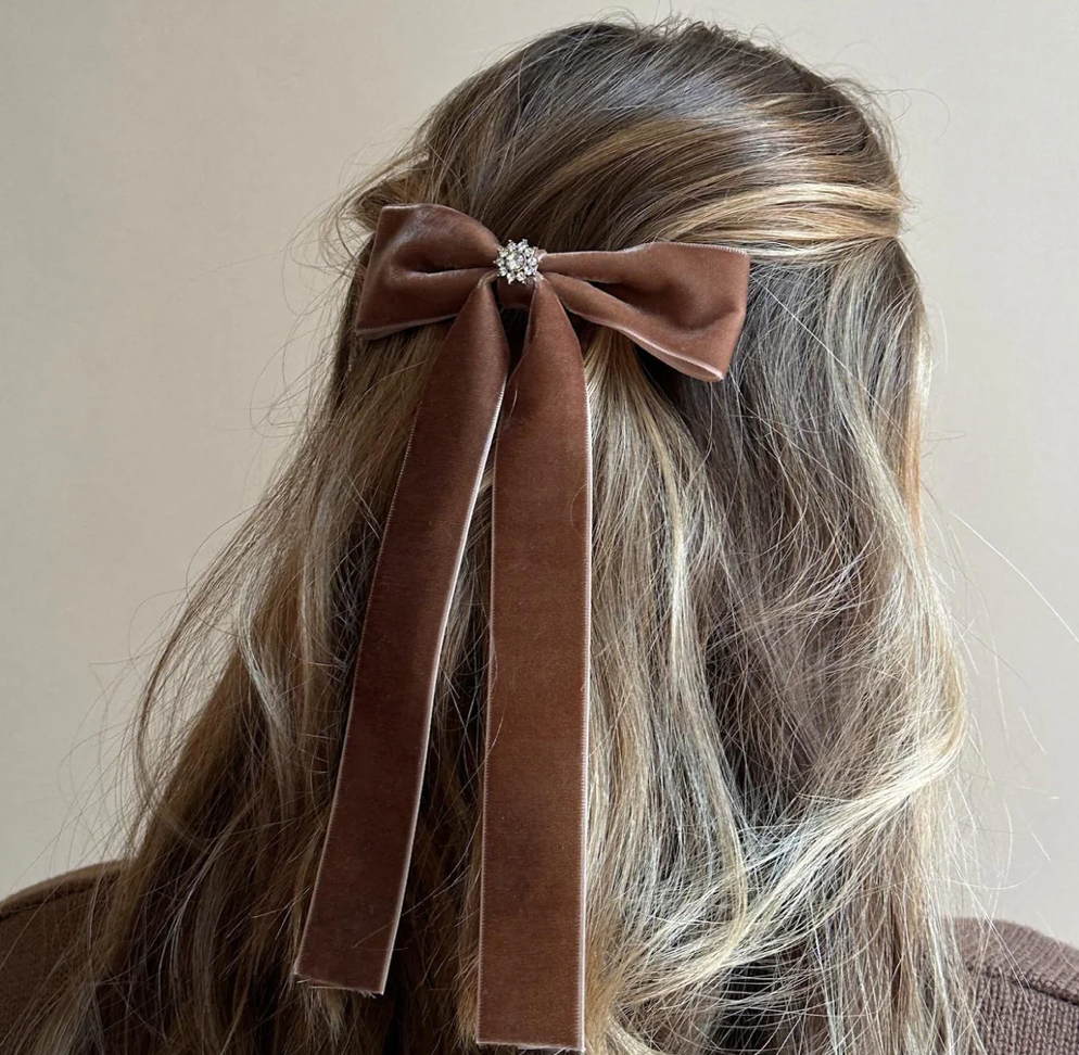 Brown velvet hair bow with crystal center and long ribbon tails in half-up hairstyle