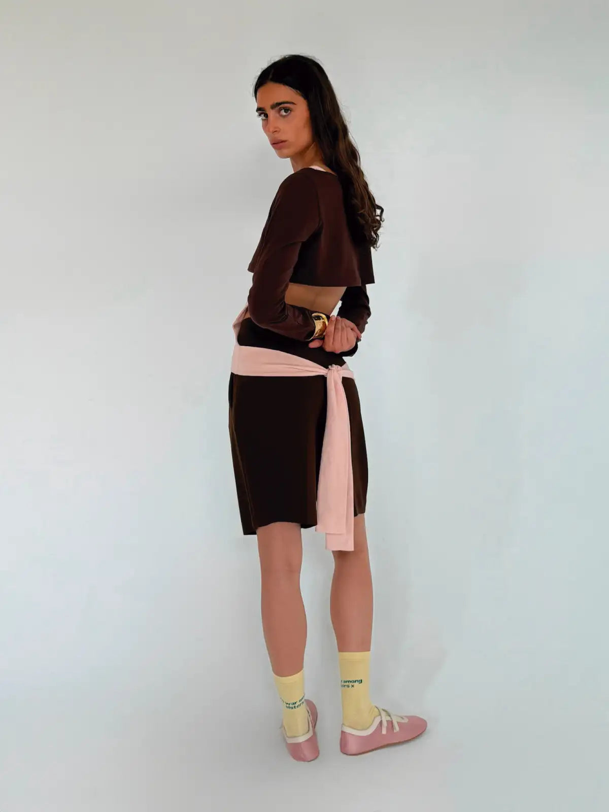 Brown cropped jacket with color-block design, featuring pink tie waist detail, worn with matching shorts and yellow socks