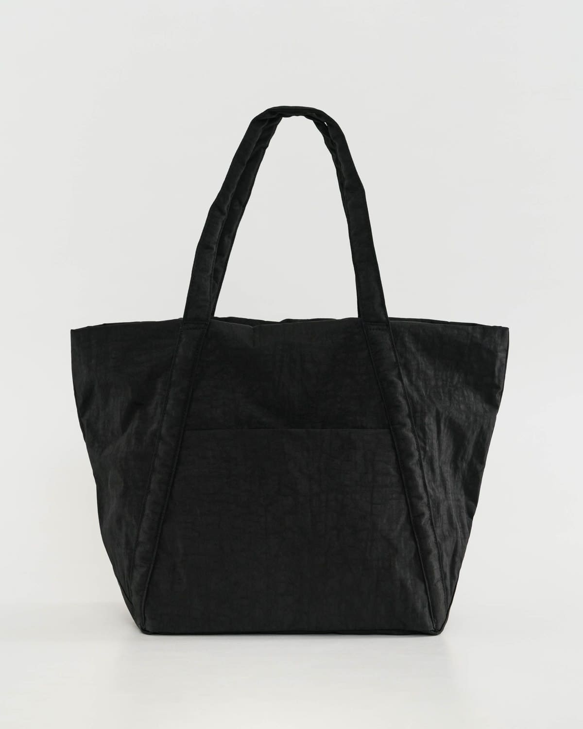 Black leather tote bag with twin handles and front slip pocket against light gray background