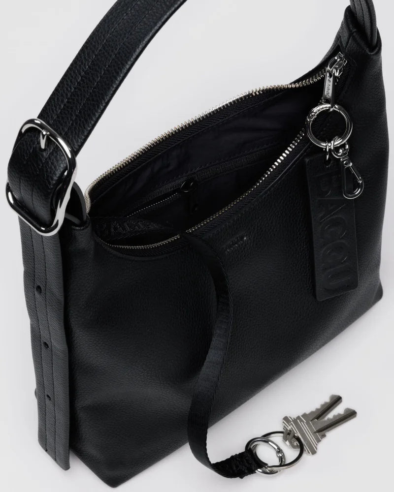 Black leather crossbody bag with silver hardware, adjustable strap, front pocket, and key fob attachment shown partially unzipped