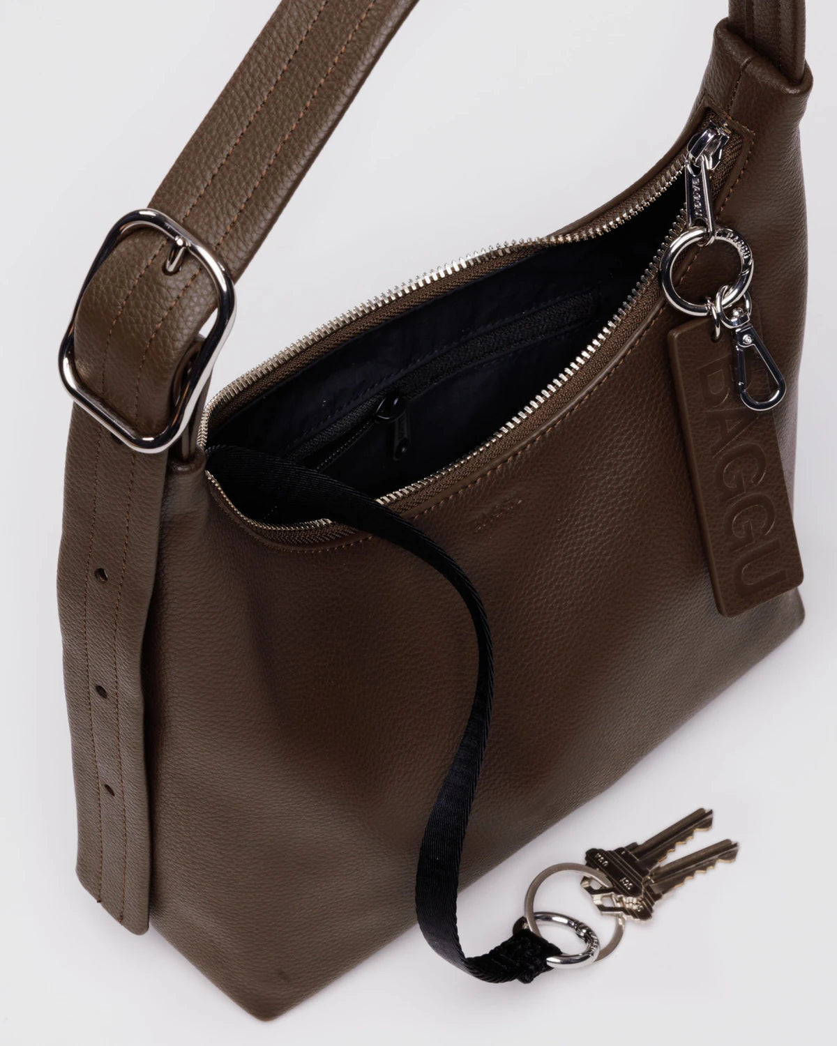 Brown leather crossbody bag with adjustable strap, silver zipper closure, and keychain attachment shown partially open